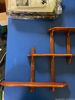 Photo of three-level wooden wall shelves mounted on blue background, showing structure and shelf sizes