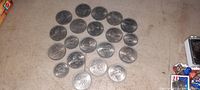 20 vintage foreign coins arranged on beige surface showing various profiles and designs