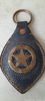 Front view of antique leather horse saddle ornament featuring a brass star and ring