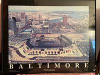 Framed aerial photo of Baltimore's Camden Yards stadium, showing surrounding buildings and the stadium roof with large crowd.