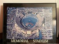 Framed aerial photo showing full stadium from above with crowd and surrounding parking lots.