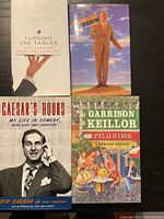 Photo of four books showing their front covers: 'Turning the Tables' with a hand holding a plate, Steve Martin in a suit on a pedestal, 'Caesar's Hours' with a black and white photo of Sid Caesar, and 'Pilgrims' with an illustrated scene.