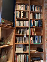 Five-shelf wooden bookcase with assorted hardcover and softcover books