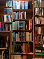 Bookshelves filled with assorted hardcover and softcover books with a variety of titles and colors.
