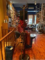 Full view of the wood coat tree standing upright in a living room with items hanging on it