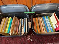 Two large plastic bins filled with various music books and sheet music in different colors and sizes.