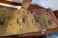 Full view of unrolled scroll on wooden surface next to textile box and cardboard tube