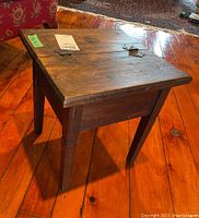 Front and top angled view of rustic wood table showing hinged top lid with metal hinges and visible wood grain and marks on surface.