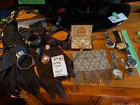 Full overview of lot showing gloves, bow ties, jewelry, watches, and purse on wooden surface