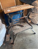 Photo of Black and Decker Workmate 300 folding workbench front view showing wooden top, grey metal frame with label, and folding mechanism.