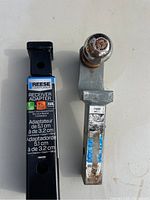 Photo displaying 2 inch receiver adapter with label Reese Towpower and metal ball mount hitch with rust signs.