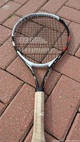 Photo of Babolat tennis racket frame and strings on brick surface, showing overall condition and design
