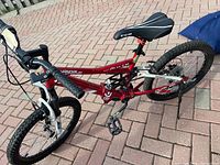 Side angled view of the red CCM Vandal 14" kids bike showing the frame, tires, pedals, chain, and Shimano rear brake.