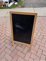 Front view of the wood framed chalkboard easel showing the black writing surface and natural wood frame.