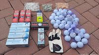 Overview of golf balls, tees in small bags, golf glove, and multiple boxes of golf balls.