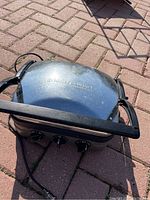 Top view of Panini grill showing the stainless steel lid with Griddle Gourmet embossed and control knobs on front panel.