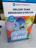Retail box showing balloon graphics and helium tank details including capacity to fill approximately 47-59 9 inch balloons or 24-27 11 inch balloons. 100% helium, 13.5 lbs net weight.
