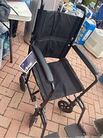 Front and side view of lightweight black aluminum transport wheelchair with padded armrests and footrests.