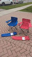 Blue and red Outbound kids folding chairs with matching carrying cases displayed on brick pavement.