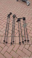 Four sets of ski poles laid on brick pavement, showing adult and youth pairs.