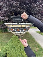 Side view of stained glass bowl shade and metal mounting canopy held outdoors