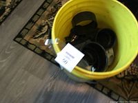 Yellow bucket filled with black ABS plumbing fittings and connectors for plumbing use.