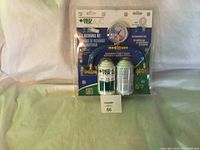 Photo of new AC recharge kit in original packaging showing green and white recharge canister, pressure gauge with blue hose, and additional white canister.