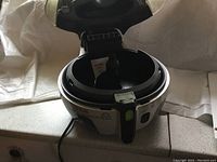 Open lid view of T-fal ActiFry air fryer revealing the interior cooking pan and mechanism, showing clean and unused condition.