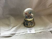 Front view of Bradford Exchange snow globe showing the figurines inside and the decorated base.