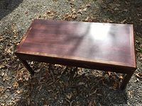 Top view of the rectangular solid wood coffee table showing darker reddish-brown finish and ware marks on the surface.