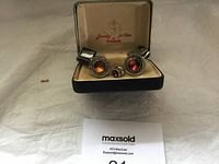 Full view of men's cufflinks, tie clasp, and small stud inside original Weber branded presentation box on white fabric surface.