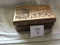 Closed view of rectangular wooden box with detailed elephant carvings on the lid, showing craftsmanship and wood texture.