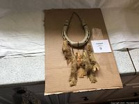 Front view of rustic horseshoe art piece with attached feathers and leather straps, placed on cardboard.