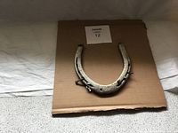 Top view of large vintage horseshoe placed on a cardboard background showing general shape and aged texture.