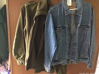 Photo showing hanging Levi's denim jacket and green military sweater on wooden hanger