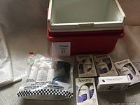 Photo showing red Coleman mini cooler, shoe care travel kit in plastic packaging, and five boxed Spectro moisturizer packs including cleanser and moisturizer products.