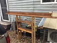 Front angled view of the 7-foot long wooden nick nack shelf showing the narrow top shelf with raised edges and wider lower shelves supported by vertical wooden slats.