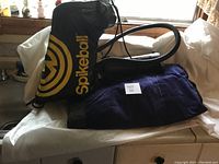 Intex single air mattress folded with quick pump and Spikeball game bag on a table surface near a window.