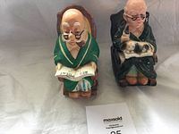 Photo of two vintage grandpa coin banks side by side on white fabric background with MaxSold auction card.