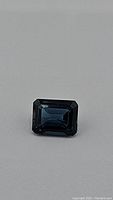 Close-up image of rectangular emerald cut London blue topaz showing deep blue color and facets.