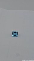 Swiss Blue Topaz gemstone, emerald cut, viewed from top showing sharp facets and vibrant blue color.