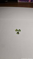 Three small apple green peridot gemstones in a triangular shape, shown against a white background.
