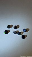 Multiple black opal gemstones in fancy diamond cuts showing color flashes