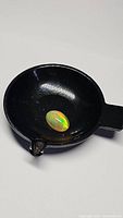 Oval cabochon Ethiopian opal in a black dish showing color flashes and honeycomb pattern.