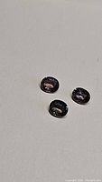Three loose oval sapphires on white background, showing colors and clarity.