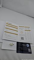 Ring displayed alongside opened GRA moissanite grading report and warranty card