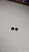 Pair of deep blue round cabochon Lapis Lazuli gemstones on a white background, showing size and color.