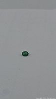 Photo of a single oval cut natural emerald 0.62ct, rich green color and high luster, approx 7x5mm size.