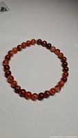 Stretchy bracelet made of round polished red agate beads, showcasing the natural banded patterns and color variations.