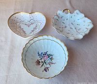 Overview of three vintage ornate porcelain Japanese bowls: heart-shaped, leaf-shaped, and round scalloped with floral designs and gold trim.